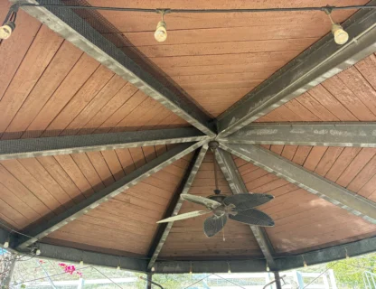 A clean and well-maintained gazebo ceiling with a fan and decorative lighting.