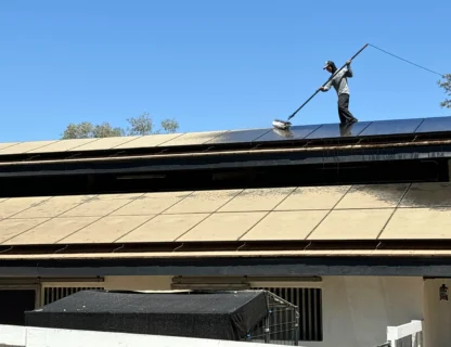 Worker cleaning a roof with a long pole and brush